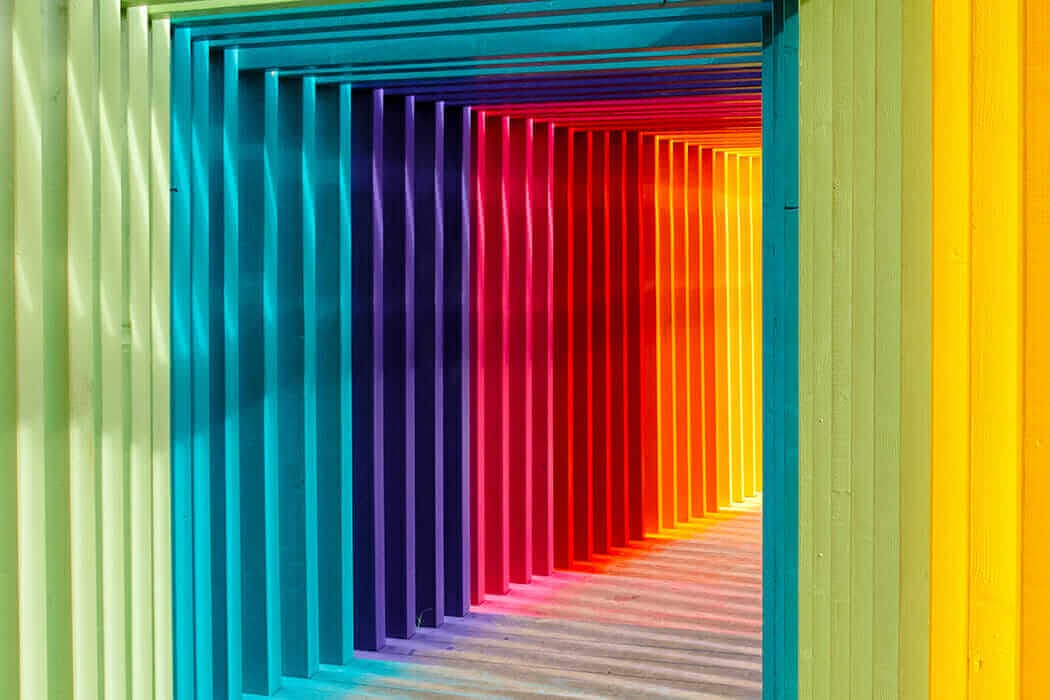 Colorful rainbow doors creating a vibrant and artistic tunnel effect, showcasing a spectrum of vivid colors in a linear pattern.