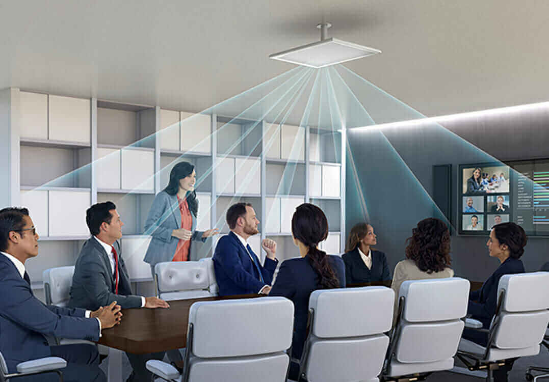 Conference room with diverse professionals, overhead microphone system, and video conferencing screen.