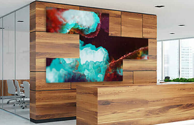 Modern office lobby with artistic video wall display, featuring abstract colorful visuals on wooden panel backdrop.