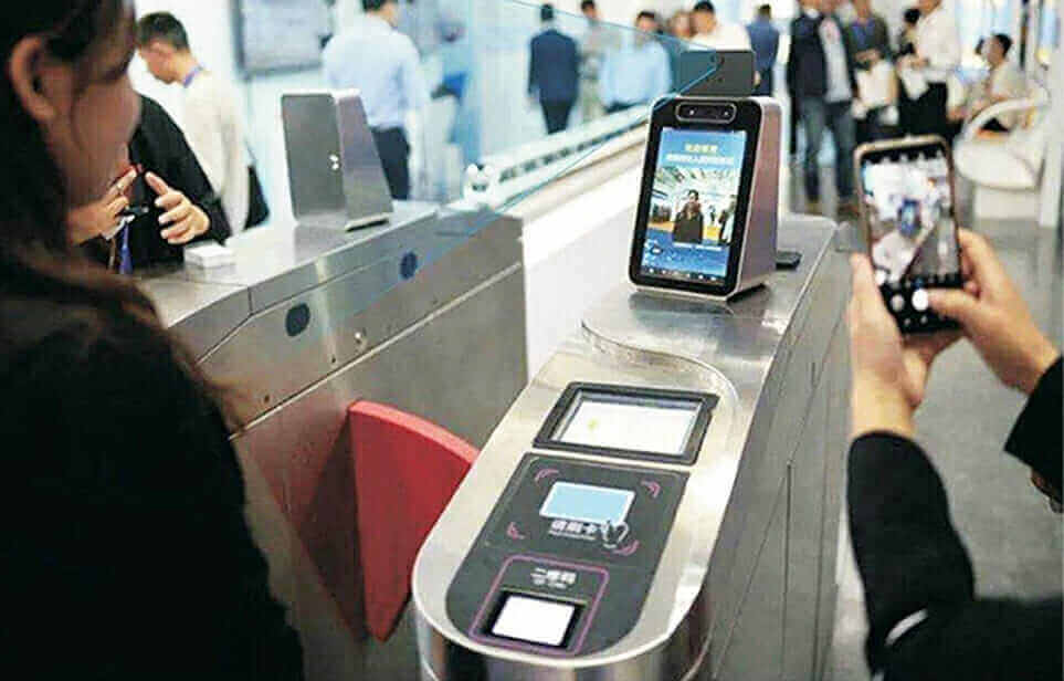 Facial recognition turnstile system with smartphone integration in busy public transit area.