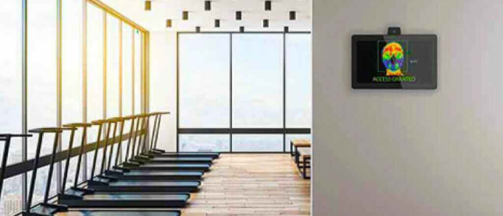 Modern gym with treadmills and large windows, featuring digital screen on wall, bright and spacious workout area.