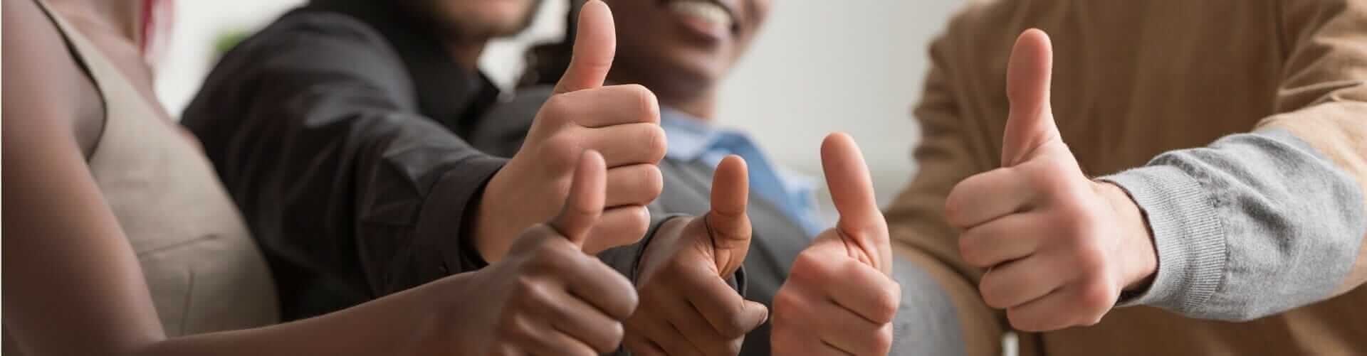 Diverse group giving thumbs up, showing teamwork and positivity, close-up of hands, multicultural collaboration concept.