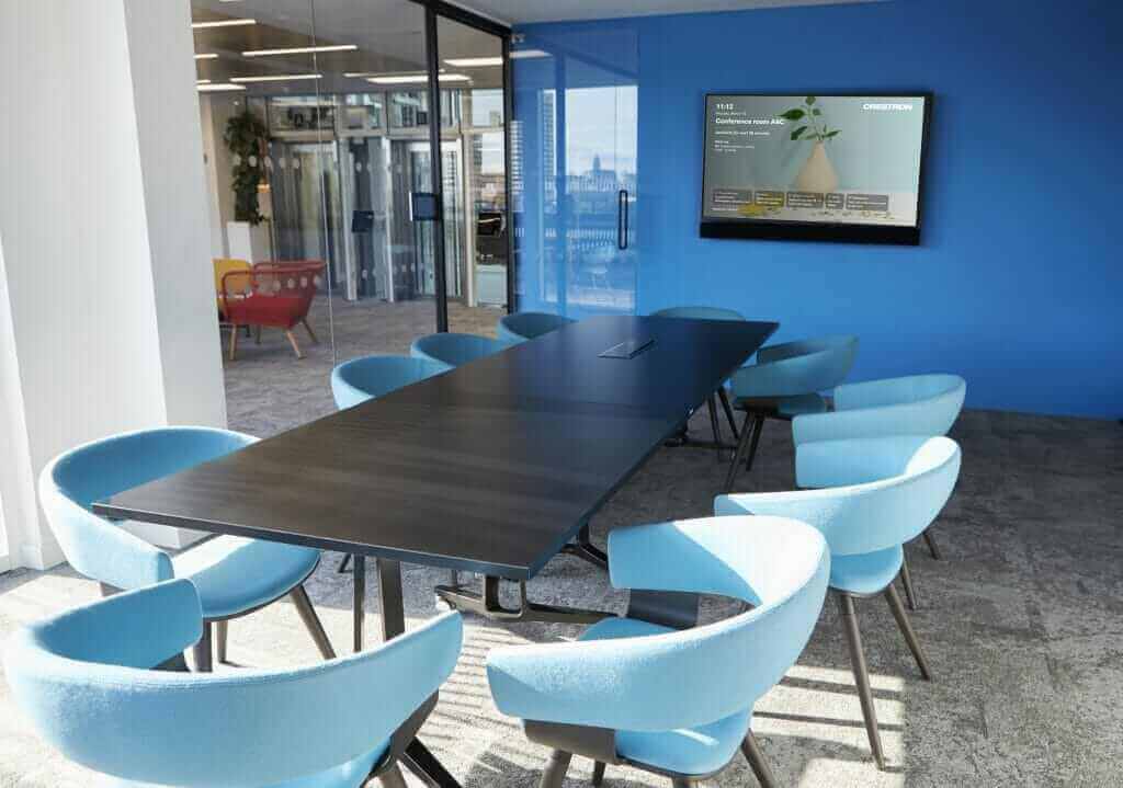 Modern empty business meeting room with blue walls, large table, and chairs in a bright office space.