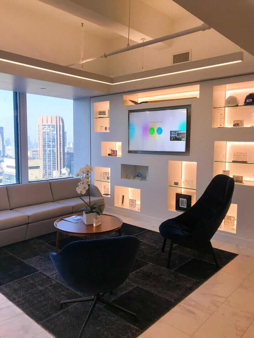 Modern Meridiam huddle room with sleek furniture, large windows, and wall-mounted screen in contemporary office setting.